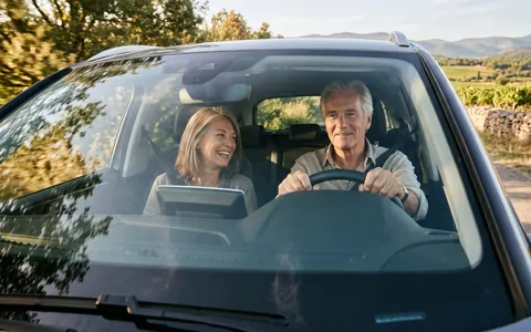 Couple au volant de sa voiture neuve sur une route de campagne